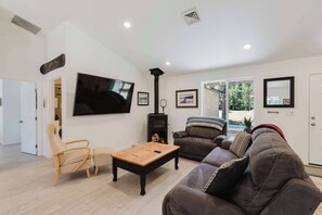A living room with a flat-screen TV, a fireplace, a sofa, a coffee table, and a door leading to another room.