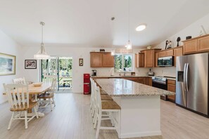 A modern kitchen with wooden cabinets, stainless steel appliances, and a large island.
