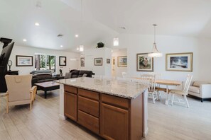Un amplio espacio de sala con una isla grande en la cocina, gabinetes de madera y una mesa de comedor con sillas.