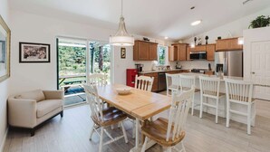 Eine moderne Küche mit Holzschränken, einem Edelstahlkühlschrank und einem Essbereich mit Holztisch und weißen Stühlen.