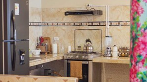 A kitchen with a refrigerator, stove, oven, and tiled backsplash. - View of the Mountains! Private home with a terrace, ideal for families (Ollantaytambo)
