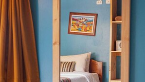 A bedroom with a bed, a wooden headboard, a wall-mounted shelf, and a painting. - View of the Mountains! Private home with a terrace, ideal for families (Ollantaytambo)