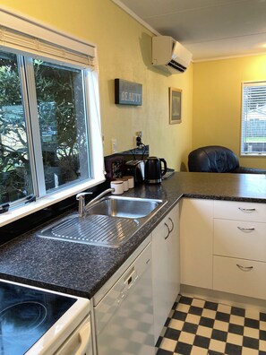A kitchen with a built-in stove, a sink, and a window with blinds.