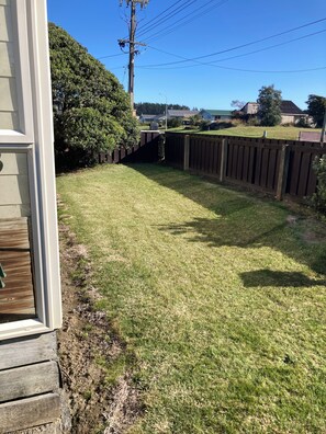 A residential backyard with a wooden fence, a well-maintained lawn, and a house in the background.