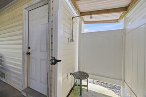 A covered porch with a door, a small table, and a hose. - Carolina Sol | 560 ft to the beach | Private Pool and Community Pool (Nags Head)