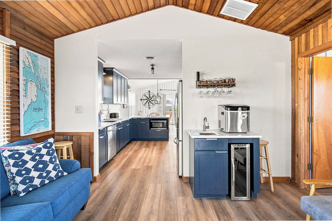Une cuisine compacte dotée d’un îlot central, d’un plancher en bois et d’un coin repas avec un canapé bleu.