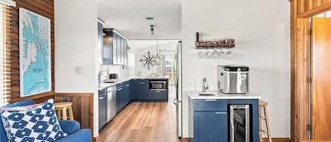 Cocina compacta con isla central, piso de madera y zona de comedor con sofá azul.