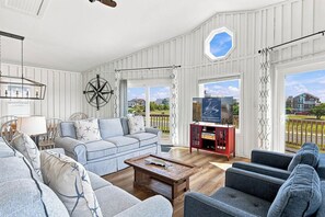 Un salón espacioso con un gran ventanal, una mesa de centro de madera y un televisor sobre un mueble.