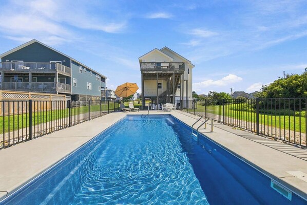 Una piscina con vista a dos edificios, uno con balcón y otro con escaleras.
