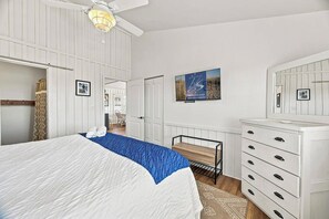 A hotel room with a bed, a desk, a dresser, and a ceiling fan. - Carolina Sol | 560 ft to the beach | Private Pool and Community Pool (Nags Head)