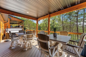 Eine Terrasse im Freien mit Holzmöbeln, einem Grill und Blick auf den Wald.