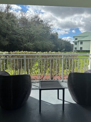 A balcony with a white railing, two wicker chairs, and a small table. - Modern Luxury one bedroom apartment in Doral Florida! (Doral)