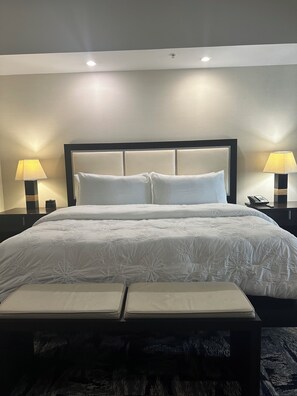 A hotel room with a large bed, two bedside lamps, a bedside phone, and a bench at the foot of the bed. - Modern Luxury one bedroom apartment in Doral Florida! (Doral)