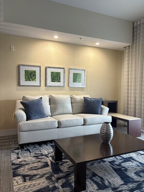 A living room with a sofa, a coffee table, and three framed pictures on the wall. - Modern Luxury one bedroom apartment in Doral Florida! (Doral)