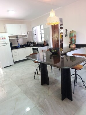 Een moderne keuken met witte kasten, een zwart aanrecht en een eettafel met stoelen.