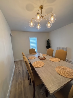 A dining room with a wooden table, woven placemats, and a chandelier with multiple bulbs. - Stylish and cozy retreat, Utica (Utica)