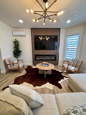 A modern living room with a central round table, two armchairs, a large mirror, and a ceiling light fixture. - Stylish and cozy retreat, Utica (Utica)