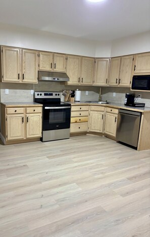 A kitchen with wooden cabinets, a stainless steel oven, a microwave, and a dishwasher. - Stylish and cozy retreat, Utica (Utica)