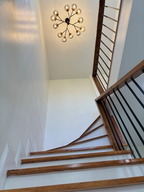Una escalera con escalones de madera y una lámpara moderna.