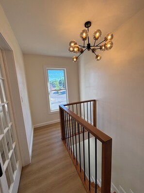 Un escalier avec une rampe en bois et un lustre en verre.