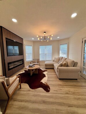 Una sala de estar moderna con televisor de pantalla plana, un sofá, una mesa de centro y una chimenea.