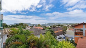 A residential area with a view of distant hills, houses with red-tiled roofs, and lush green vegetation. - Complete Studio 900 m From Lagoa Ecm0206 (Florianópolis)