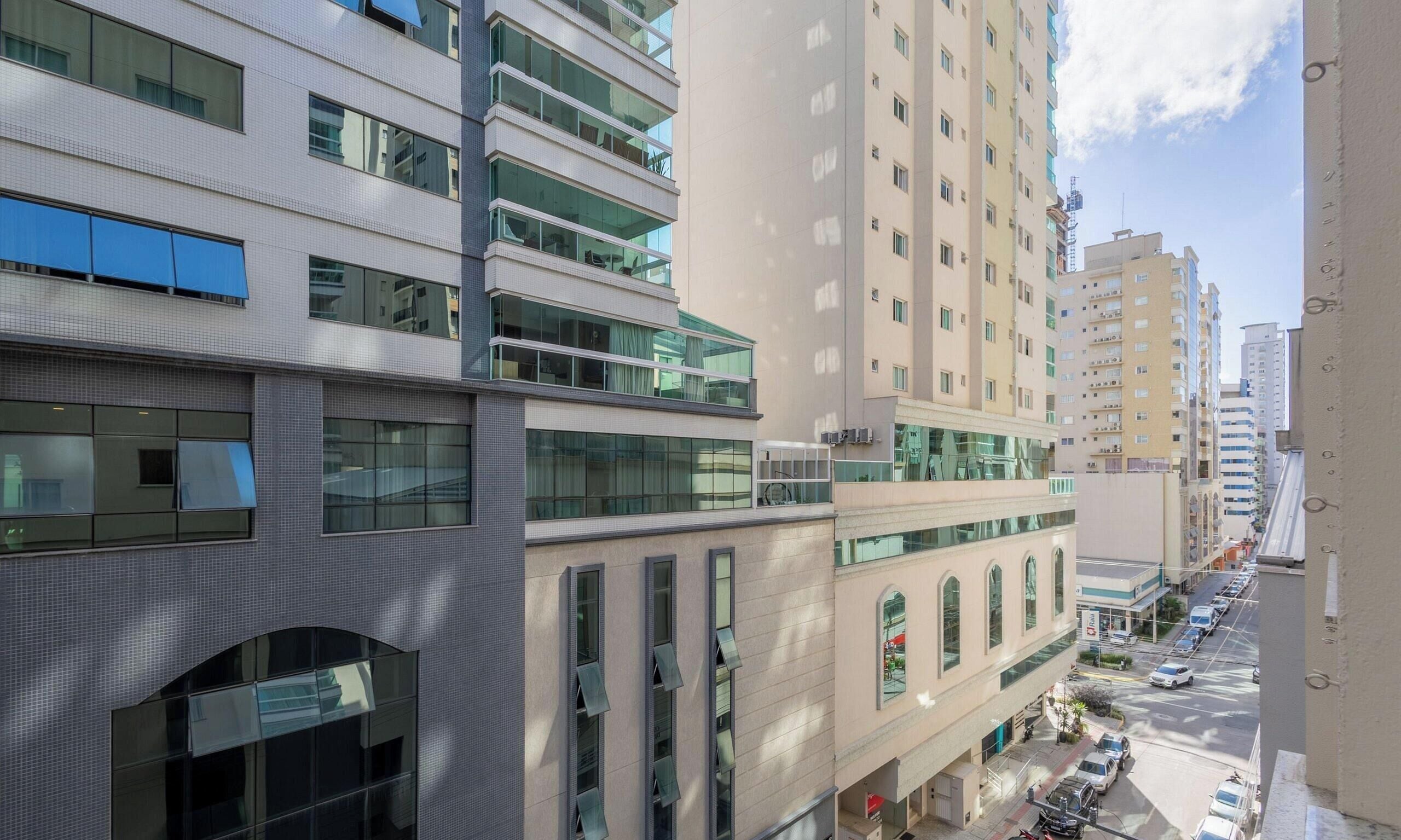 Um edifício de vários andares com grandes janelas, fachada plana e área de estacionamento na frente.