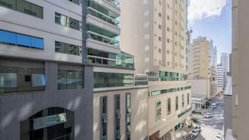 Um edifício de vários andares com grandes janelas, fachada plana e área de estacionamento na frente.