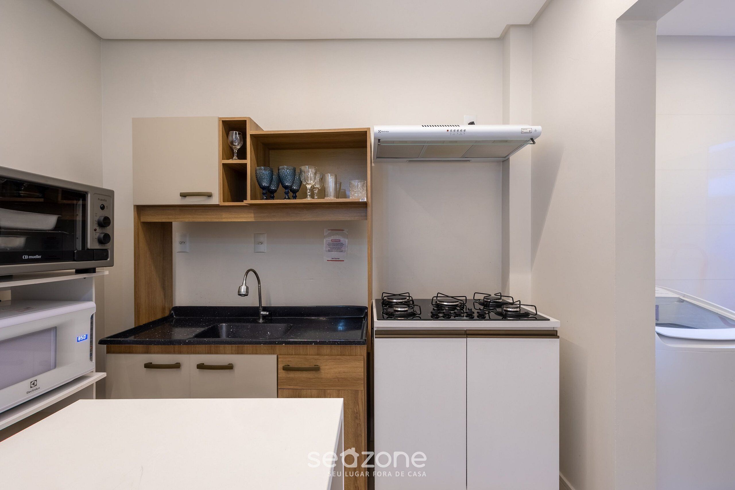 Cozinha compacta com micro-ondas, forno, pia e fogão a gás.