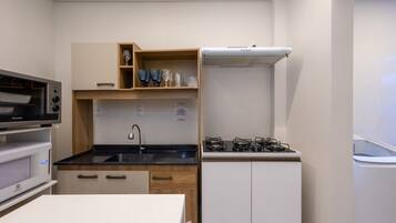 Cozinha compacta com micro-ondas, forno, pia e fogão a gás.