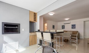 Una cocina moderna con horno empotrado, un comedor con mesa y sillas, y una sala de estar con sofá.