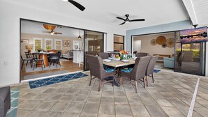 A spacious dining area with a high ceiling, multiple ceiling fans, and a large window offering a view of the outdoors. - VILLA RIVERSIDE– HEATED POOL | GULF ACCESS | BOAT RENTAL + TOURS VOUCHER INCL. (Cape Coral)