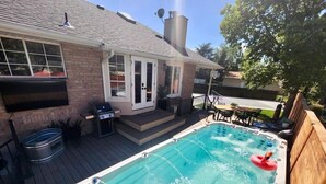 Een achtertuin met een jacuzzi, een terras en een huis van baksteen.