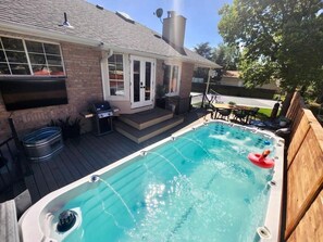 Ein Garten mit Whirlpool, einer Terrasse und einem Ziegelhaus.