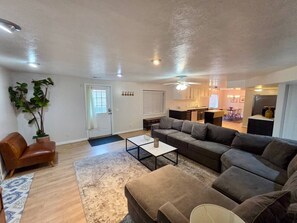 Ein Wohnzimmer mit einer Sofagarnitur, einem Couchtisch, einem braunen Ledersessel und einer großen Topfpflanze.