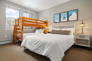 Ein Schlafzimmer mit einem Etagenbett, einem Nachttisch mit Lampe und gerahmten Bildern an der Wand.