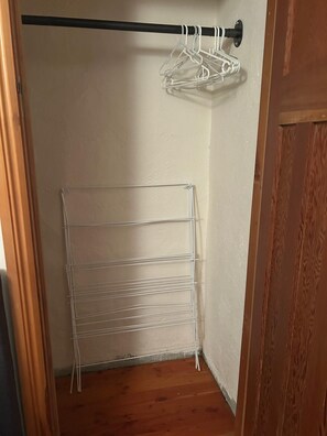 A corner closet with a metal wire shelf and a rod with white hangers.