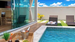 A poolside area with a glass-enclosed dining area, lounge chairs, and a small pool.
