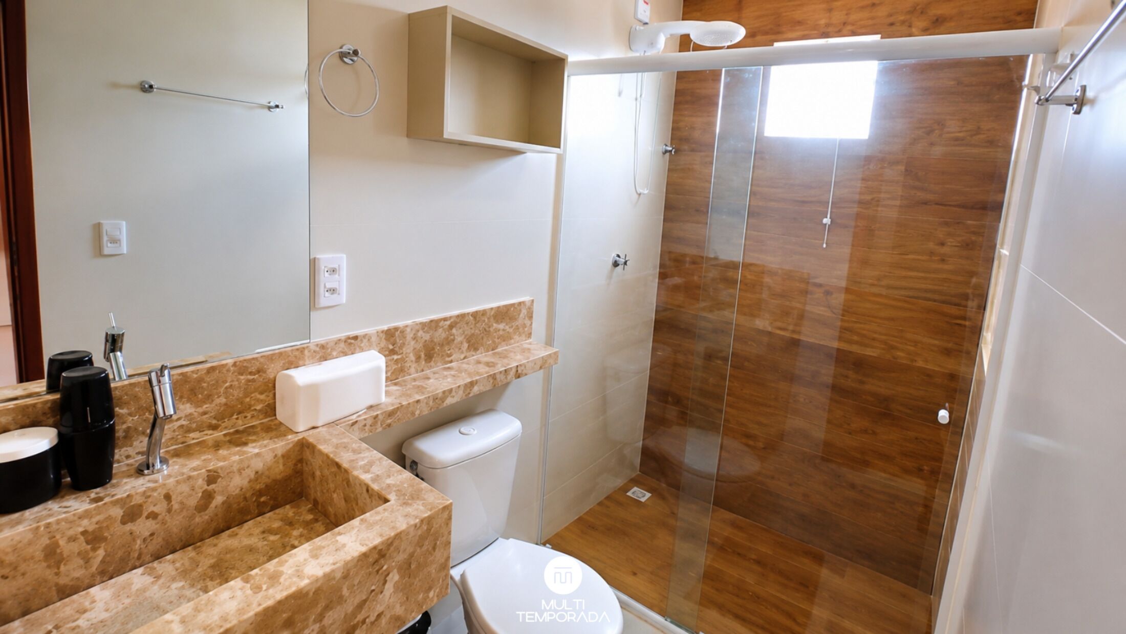 A bathroom with a marble countertop, a toilet, a shower enclosure, and a mirror.