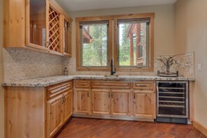A kitchen with wooden cabinets, a granite countertop, a built-in oven, and a window with a view of trees.
