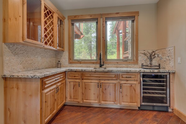 A kitchen with wooden cabinets, a granite countertop, a built-in oven, and a window with a view of trees.
