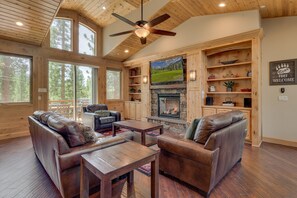 A spacious living room with leather sofas, a fireplace, and a television mounted on a wooden wall. - Game Room, Pool Table, Foosball, Arcade, Fireplace, Chef's Kitchen, Hot Tub, Sauna: Big Bear Lodge (South Lake Tahoe)