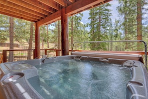 A hot tub with a wooden deck and a view of a forest. - Game Room, Pool Table, Foosball, Arcade, Fireplace, Chef's Kitchen, Hot Tub, Sauna: Big Bear Lodge (South Lake Tahoe)