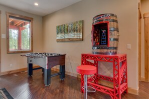 A room with a foosball table, a red bar stool, and a decorative barrel.