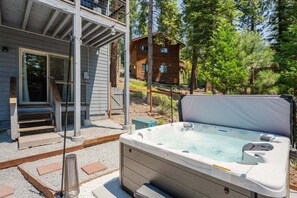 Ein Whirlpool in einem Garten mit einer Holzterrasse und einem Haus im Hintergrund.