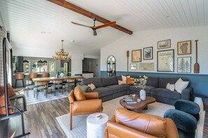 A spacious living room with a large sectional sofa, leather armchairs, a coffee table, and a dining area with a wooden table and chairs. - Karaoke, Pool Table, Arcade, Outdoor Games, Bubble Dome, Grill, Spa: Starfall Lodge (Tahoe Vista)