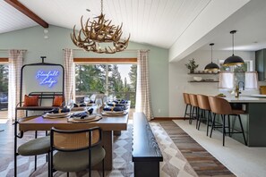 A dining area with a long table set for a meal, a bench, and a bar with stools. - Karaoke, Pool Table, Arcade, Outdoor Games, Bubble Dome, Grill, Spa: Starfall Lodge (Tahoe Vista)