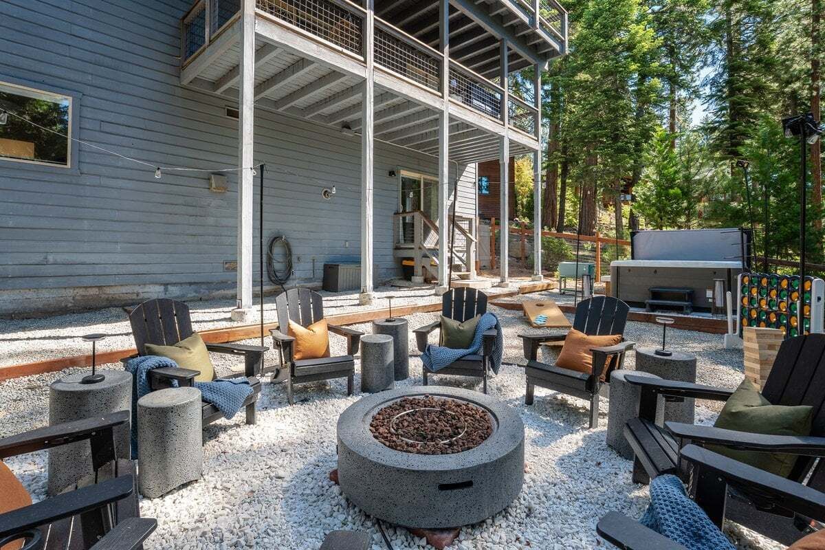 An outdoor seating area with Adirondack chairs, a fire pit, and a grill.