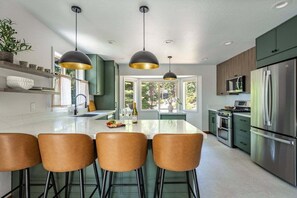 A modern kitchen with a central island, pendant lighting, and stainless steel appliances. - Karaoke, Pool Table, Arcade, Outdoor Games, Bubble Dome, Grill, Spa: Starfall Lodge (Tahoe Vista)