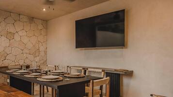 Un coin repas agrémenté d’un mur en pierre, d’un ventilateur de plafond et d’un téléviseur à écran plat fixé au mur.